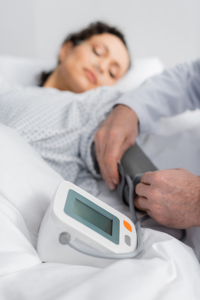 médico medición de la presión arterial de la mujer afroamericana enferma sobre fondo borroso - Foto, Imagen