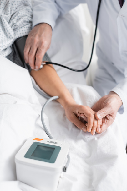 cropped view of doctor measuring blood pressure of woman in hospital - Фото, зображення