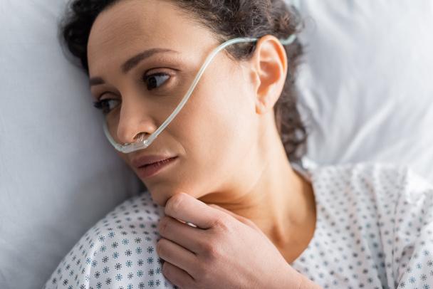 вид зверху хвора афроамериканка лежить в лікарняному ліжку з носовою канюлею
 - Фото, зображення