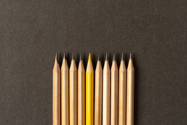 Um lápis amarelo que se destaca da série de lápis cinzentos. - Foto, Imagem