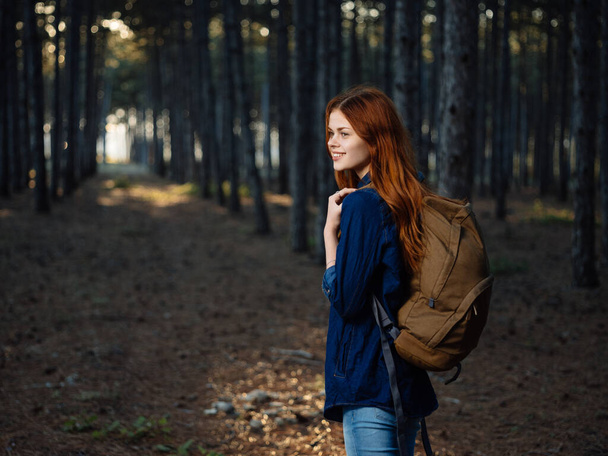 Gelukkig reiziger met een rugzak op haar rug rust in de natuur in een dennenbos - Foto, afbeelding