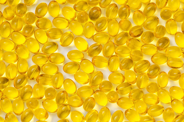 Beyaz arka planda sarı şeffaf haplar. D3 vitaminli haplar. - Fotoğraf, Görsel
