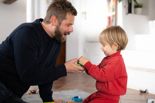 Cute little boy and father playing with toy car on floor at home - Photo, Image