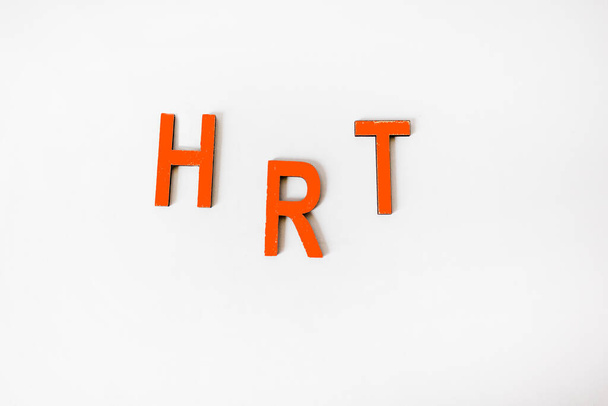 Abreviatura de la terapia de reemplazo hormonal HRT en letras rojas de madera y fondo blanco - Foto, imagen
