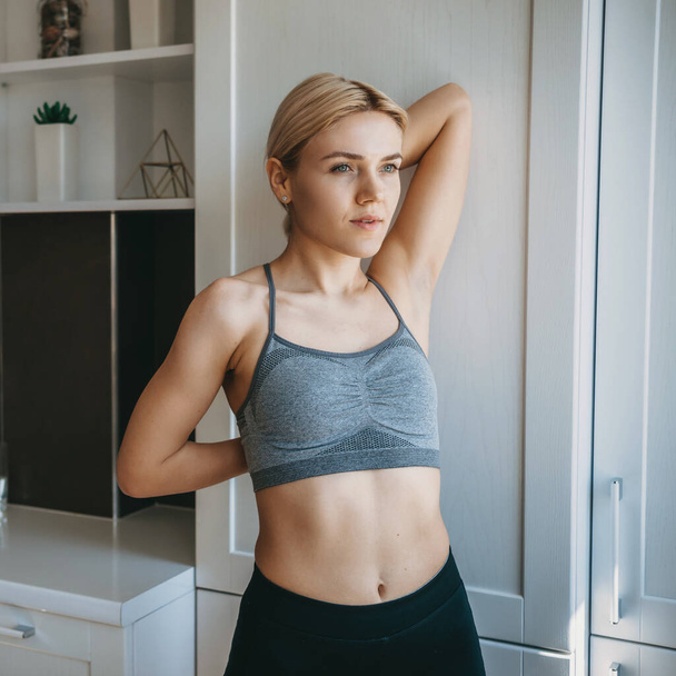 Caucasian woman is stretching at home during a fitness session at home - Photo, Image