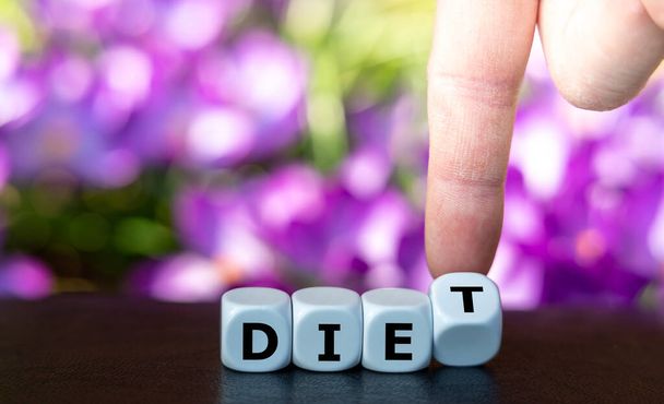 Símbolo para iniciar una dieta. La mano gira los dados y cambia la palabra "morir" a "dieta". - Foto, Imagen