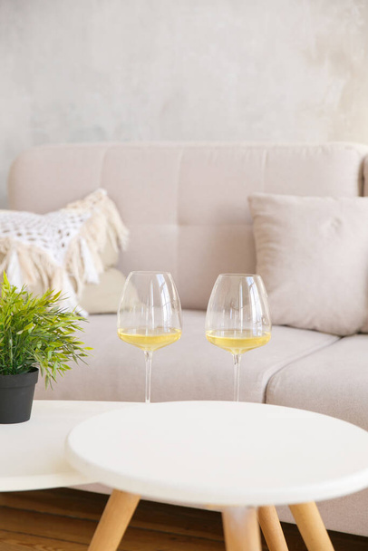 Two glasses of white wine are on the side table near the window - Photo, Image