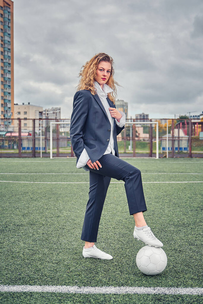portrait of  beautiful girl football player in man's suit on soccer field with ball - Photo, image
