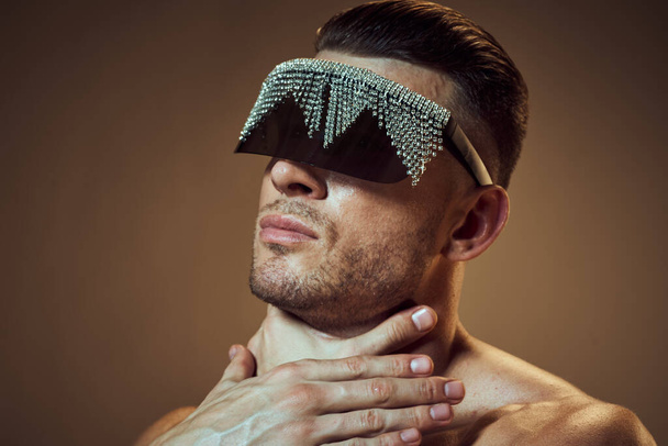 сексуальный мужчина в очках со стразами касается шеи рукой и голыми плечами модели - Фото, изображение