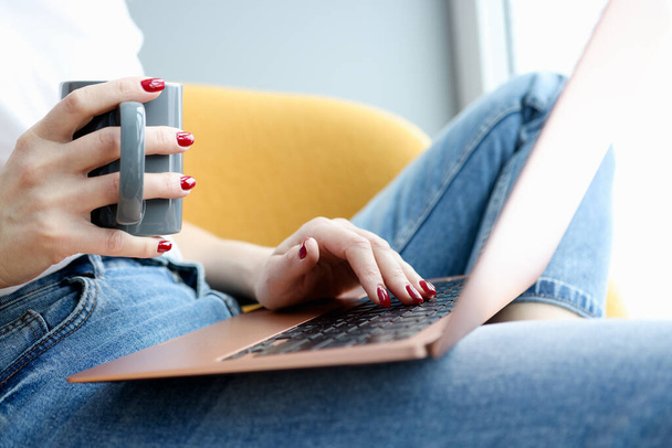 Female hands on laptop keyboard with cup - 写真・画像