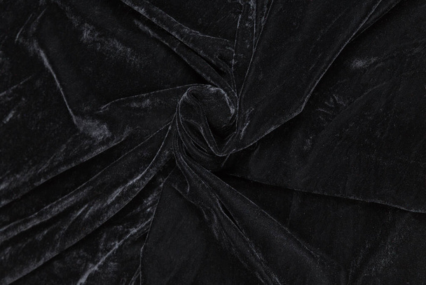 Colored black textile satin fabric folded in folds and waves with highlights and texture shimmers in the light - Foto, afbeelding
