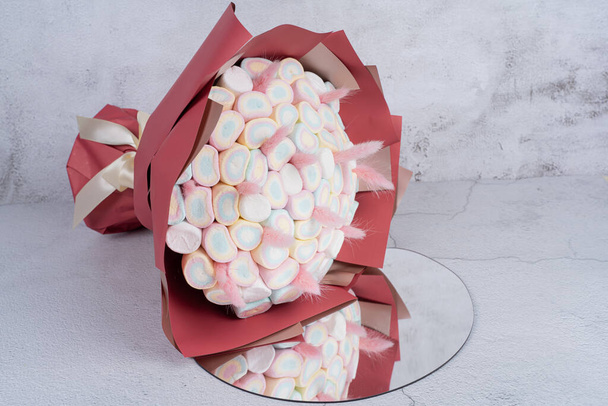 O buquê doce de doces de Marshmallows, belamente decorado, está em um fundo cinza - Foto, Imagem