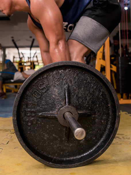 Un haltère sur le sol d'une salle de gym hardcore, utilisé pour l'exercice de deadlift. - Photo, image