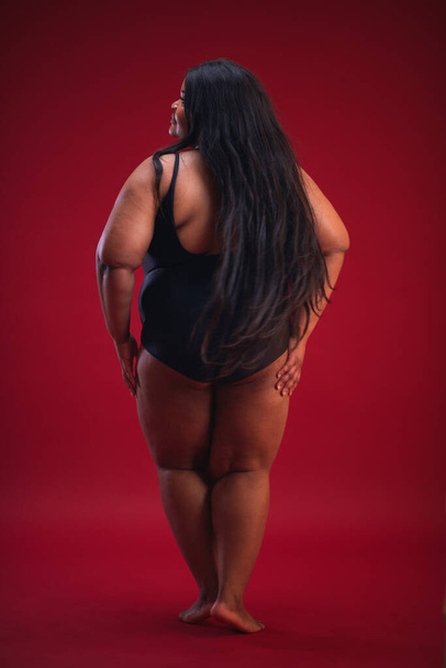 young plus size woman in swimsuit on the red background - Фото, изображение