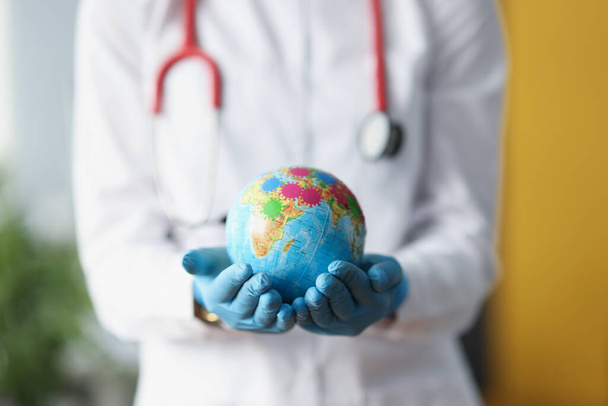 Doctor in protective gloves holding globe with viruses closeup - Photo, image
