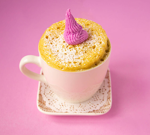 Vanilkový muffin v hrnku. Malý košíček v šálku na talíři  - Fotografie, Obrázek