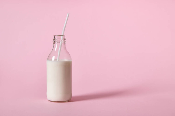 Estudio de botella de vidrio con leche, para el Día Internacional de la Leche. Aislado sobre fondo rosa con espacio para texto - Foto, Imagen