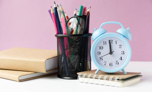 Alarm clock on wooden table on background in classroom, back to school concept - Fotó, kép