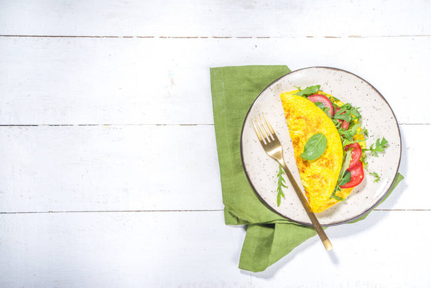 Jarní zdravá strava koncepce potravin. Míchaná vejce, plněná omeleta s čerstvou zeleninou, rajčaty, rukolou, salátem, na bílém podkladovém prostoru - Fotografie, Obrázek