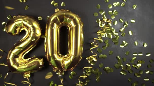 20-as számú arany fólia lufi. Születésnapi vagy évfordulós üdvözlőlap felirattal 20. Fekete beton háttér. Évfordulós ünneplés. másolás helye - Felvétel, videó