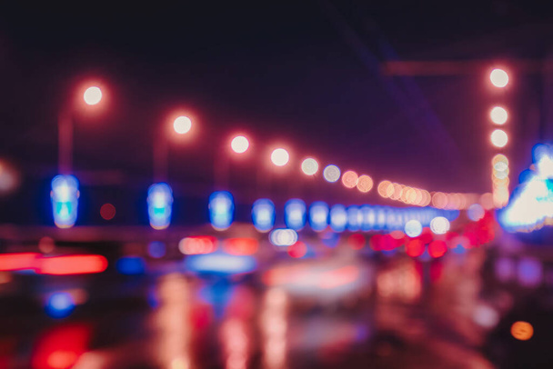 Hareket halindeki araba ve fenerlerin bulanık ışıkları gece şehrindeki ıslak asfalta yansıyor. Soyut parlak bokeh. - Fotoğraf, Görsel