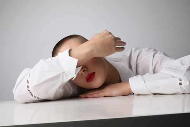Close-up of young bald woman closing her face with hand. Studio shot. - 写真・画像
