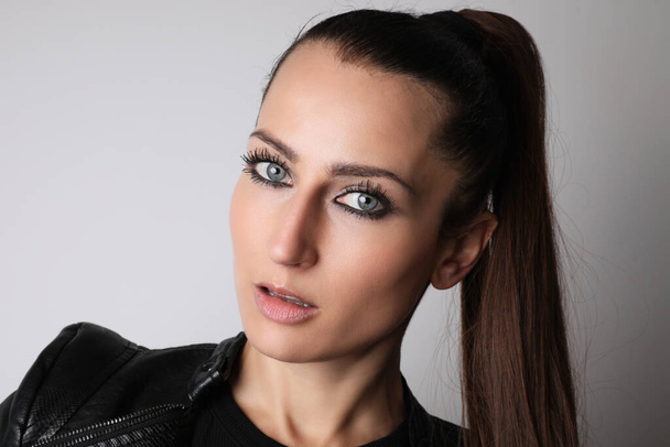 Close-up portrait of attractive woman wearing black clothing. Light background. - Fotografie, Obrázek
