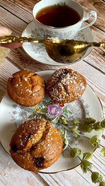 festive tea party with black tea and milk, homemade muffins, and dried herbs for mood on a wooden background and vintage English porcelain - Photo, Image