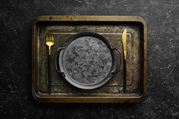 Vintage cutlery and metal plate. On a black stone background, top view. - Fotó, kép