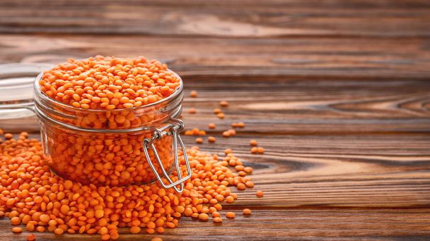 Glass jar of red lentils on wooden table with copy space. - Foto, Imagem