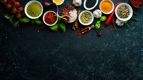 Set of Indian fragrant spices and herbs on a black stone background. Top view. Free space for text. - 写真・画像