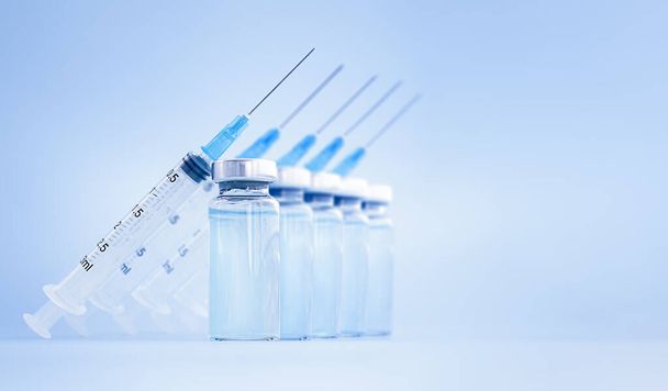 a vakcina palackok és fecskendők kék alapon egymás után vannak - Fotó, kép