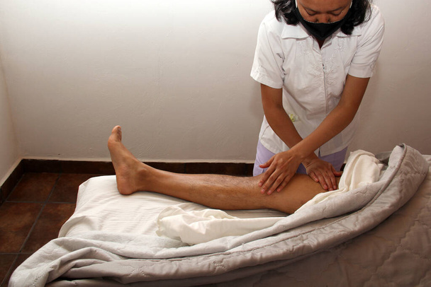 Masseuse latine travaillant sur les jambes, massage relaxant et thérapeutique. physiothérapie - Photo, image