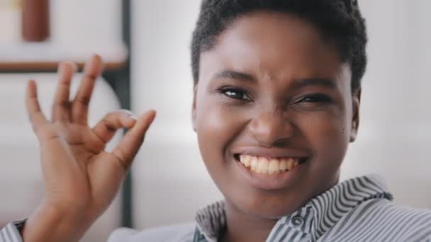 Portrét afro-americké ženy, podnikatelky, ženy, která se dívá na kameru a upřímně se usmívá na znamení "ok". Close-up smíšené závod afro černošky dáma model krátké vlasy dívka dělá OK gesto úspěch symbol - Záběry, video