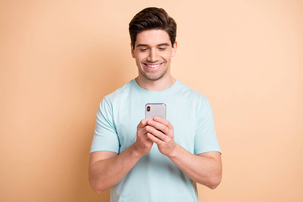 Portrait of attractive focused guy using device gadget browsing media smm isolated over beige pastel color background - Fotó, kép