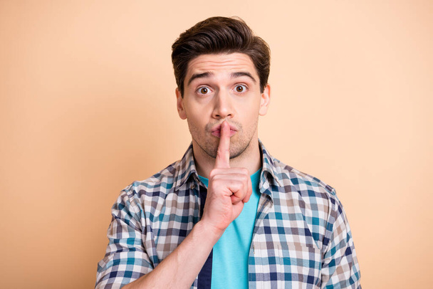 Close-up portrait of attractive funky mysterious guy showing shh sign isolated over beige pastel color background - Φωτογραφία, εικόνα