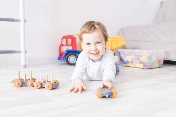 Junge spielt zu Hause auf dem Fußboden mit Holzspielzeug - Foto, Bild