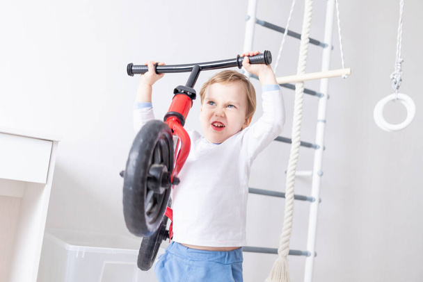 baby boy keeps running bike at home, the concept of playing and entertaining a child - Foto, Imagen