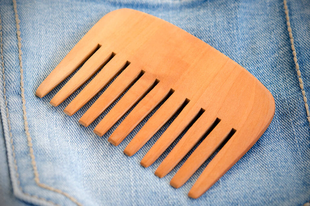 wooden comb on blue jeans background close up - Photo, Image