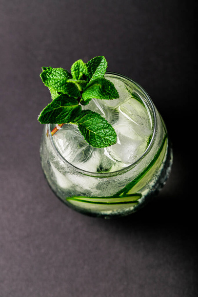glass of water with cucumber and mint on a black background - Photo, image