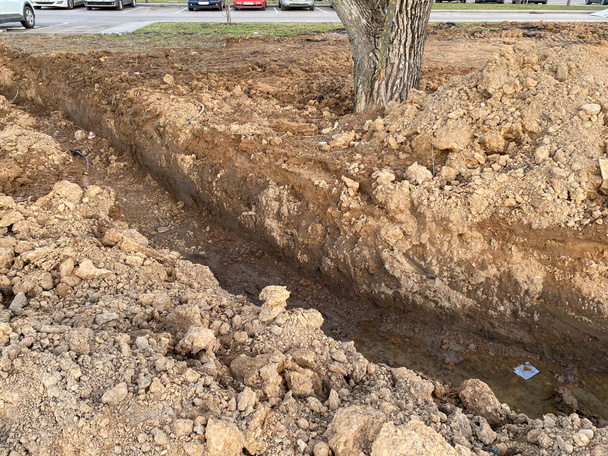 Una fossa scavata è un fosso per la posa di cavi e fili con tubi sotto terra durante la costruzione e la riparazione di case nella città della megalopoli. - Foto, immagini