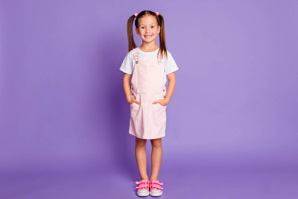 Full size photo of positive happy little girl nice smile hands in pockets isolated on purple color background - Fotografie, Obrázek
