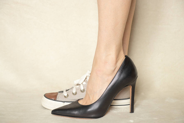 zapatilla deportiva y zapatos clásicos de tacón alto negro en los pies de la chica, la elección de los zapatos, qué ponerse - Foto, Imagen