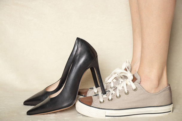 スポーツスニーカーと女の子の足に黒の古典的なハイヒールの靴、靴の選択、何を着用する - 写真・画像