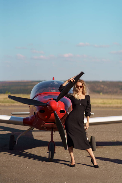 Λαμπερή γυναίκα που ποζάρει στο φόντο του αεροπλάνου - Φωτογραφία, εικόνα
