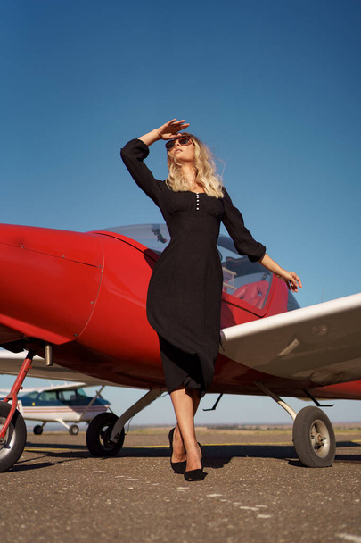 Гламурна жінка позує на фоні літака
 - Фото, зображення