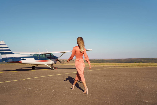 Glamouröse Frau posiert auf Flugzeug-Hintergrund - Foto, Bild