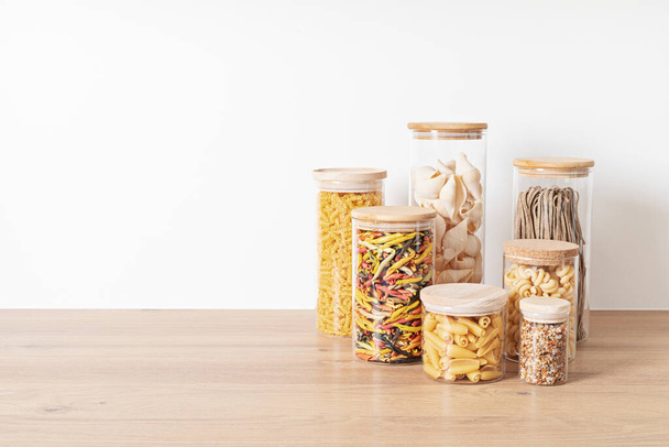 Assortment of italian traditional pasta in glass jars on wooden table. Healthy balanced food, sustainable lifestyle, zero waste eco friendly concept. - Photo, Image