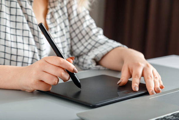 Closeup woman designer editor or photographer use graphics tablet laptop at home office workplace. Creative designer working with professional equipment. Stylus in hand draws on graphics tablet - Photo, image