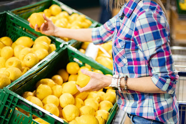 Donna che compra frutta al supermercato. Scegliere il limone. - Foto, immagini